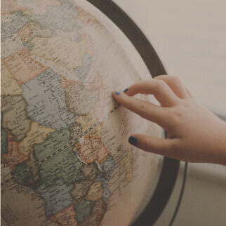 child's hand pointing to a globe